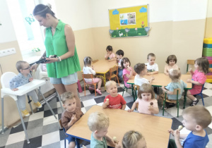 Dzieci jedzą lody przy stolikach.