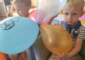 Jubilat w czapeczce urodzinowej i z balonami.