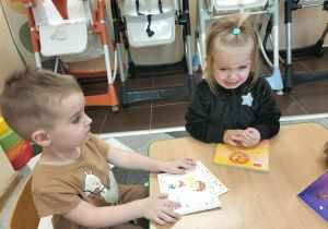 Dzieci przy stolikach robią pracę plastyczną.