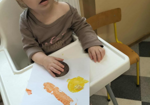 Dzieci przy stolikach robią pracę plastyczną.