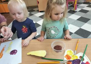 Dzieci przy stolikach robią pracę plastyczną.