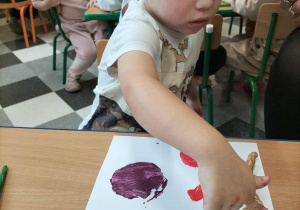 Dzieci przy stolikach robią pracę plastyczną.