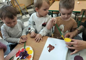 Dzieci przy stolikach robią pracę plastyczną.