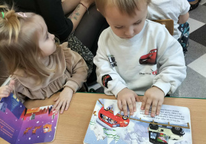 Dzieci przy stolikach robią pracę plastyczną.