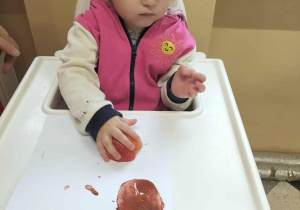 Dzieci przy stolikach robią pracę plastyczną.