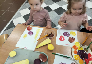 Dzieci przy stolikach robią pracę plastyczną.