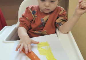 Dzieci przy stolikach robią pracę plastyczną.