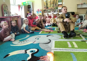 Dzieci z strażakiem oglądają noktowizjer.