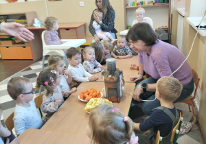 Dzieci przy stoliku z owocami i sokowirówką.