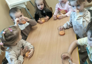Dzieci przy stoliku degustuję soczek.