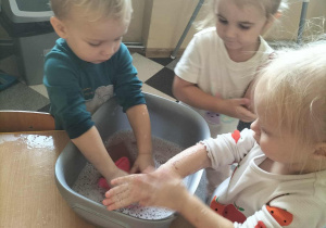 Dzieci malują drzewa przy użyciu własnych rączek.