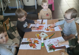 Dzieci malują drzewa przy użyciu własnych rączek.