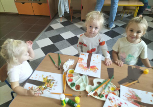 Dzieci malują drzewa przy użyciu własnych rączek.