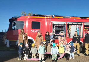 Dzieci na tgle wozu strażackiego.