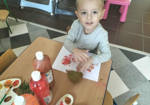 Dzieci przy stolikach malują liście.