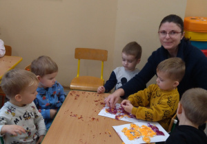 Dzieci przy stolikach robią misia z wełenki.