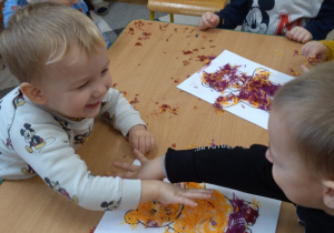 Dzieci przy stolikach robią misia z wełenki.