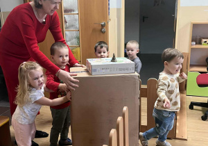 Ciocia z dziećmi wnoszą prezent mikołajkowy.