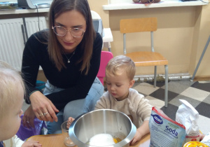 Dzieci z ciocią łączą składniki na pierniki.