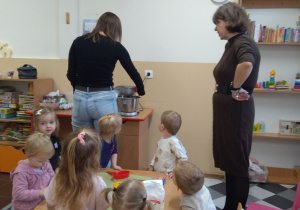 Dzieci z ciocią łączą składniki na pierniki.