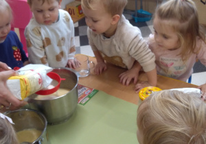 Dzieci z ciocią łączą składniki na pierniki.