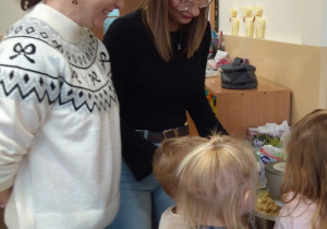 Dzieci z ciocią łączą składniki na pierniki.