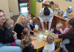 Dzieci z ciocią łączą składniki na pierniki.