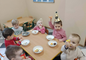 Dzieci przy stolikach podczas urodzinowego poczęstunku.