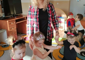 Dzieci i ciocie w przebraniach tańczą na balu.