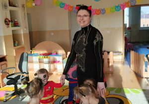 Dzieci i ciocie w przebraniach tańczą na balu.