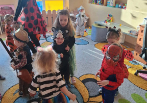 Dzieci i ciocie w przebraniach tańczą na balu.