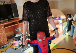 Dzieci i ciocie w przebraniach tańczą na balu.