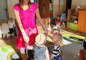 Dzieci i ciocie w przebraniach tańczą na balu.