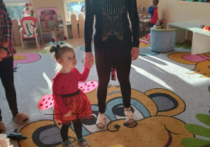 Dzieci i ciocie w przebraniach tańczą na balu.