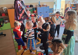 Dzieci i ciocie w przebraniach tańczą na balu.