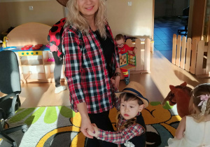 Dzieci i ciocie w przebraniach tańczą na balu.