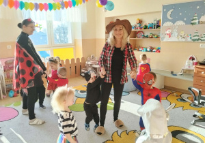 Dzieci i ciocie w przebraniach tańczą na balu.