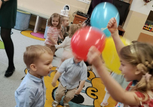 Dzieci bawią się balonami z jubilatem.