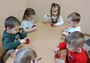 Dzieci przy stolikach podczas poczęstunku urodzinowego.