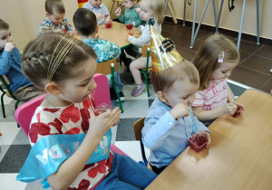 Dzieci przy stolikach podczas poczęstunku urodzinowego.
