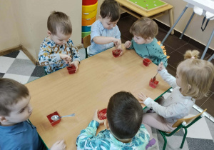 Dzieci przy stolikach podczas poczęstunku urodzinowego.