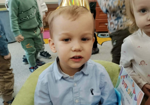 Dzieci przy stolikach podczas poczęstunku urodzinowego.