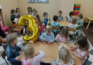 Dzieci przy stolikach podczas poczęstunku urodzinowego.