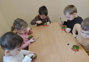 Dzieci przy stolikach podczas poczęstunku urodzinowego.