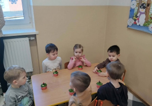 Dzieci przy stolikach podczas poczęstunku urodzinowego.