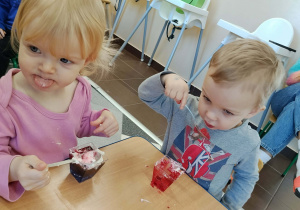 Dzieci jedzą deserki urodzinowe.