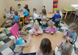 Dzieci jedzą deserki urodzinowe.