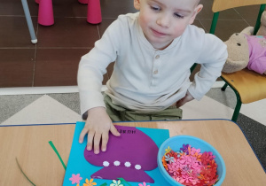 Dzieci przy stolikach robią wazoniki.