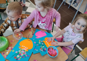 Dzieci przy stolikach robią wazoniki.