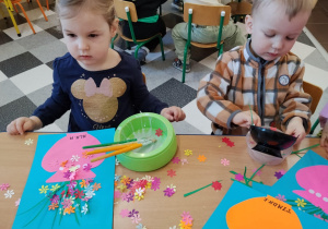 Dzieci przy stolikach robią wazoniki.